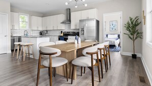 Una cucina moderna con mobili bianchi, un frigorifero in acciaio inossidabile e un tavolo da pranzo in legno con sedie.