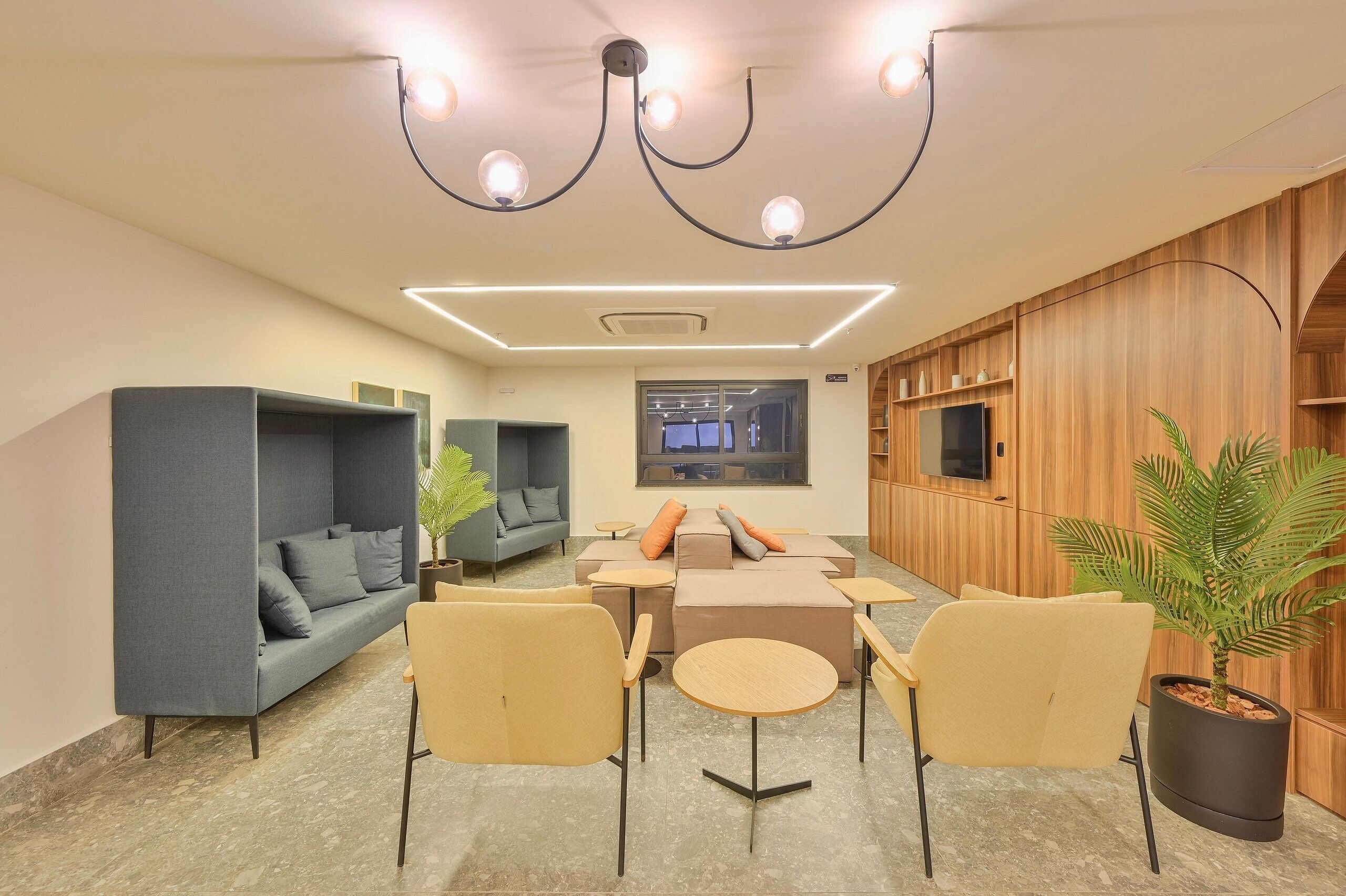 A modern lounge with sofas, chairs, a TV, and a wooden wall.