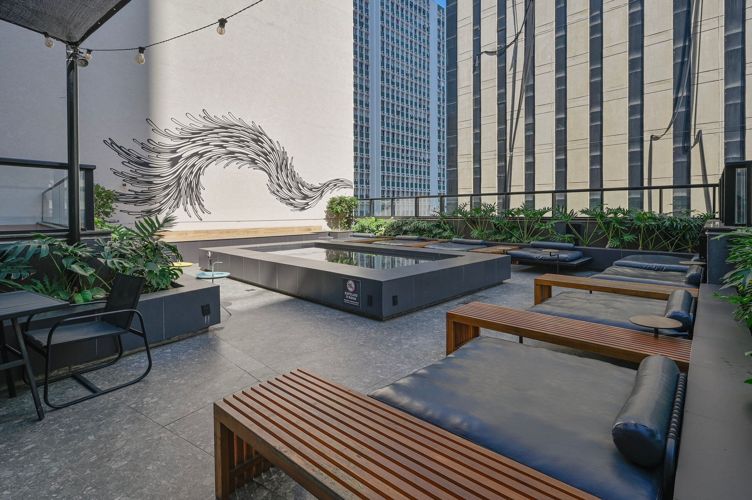 A rooftop lounge with seating, a water feature, and a mural.