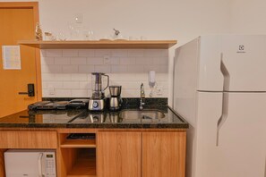 Una cocina equipada con microondas, cafetera, licuadora y refrigerador.