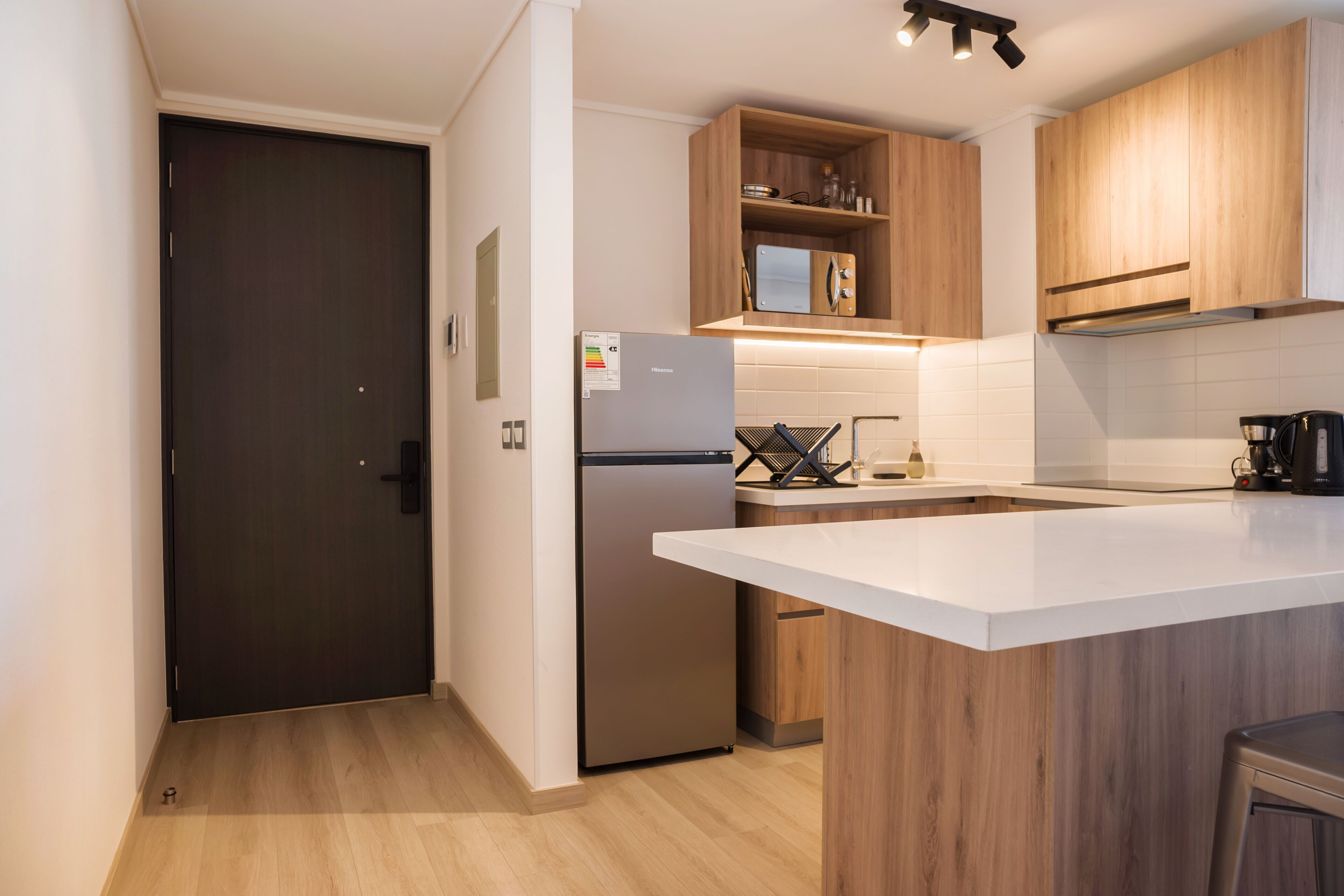 A modern kitchen with a built-in refrigerator, wooden cabinets, and a white countertop.