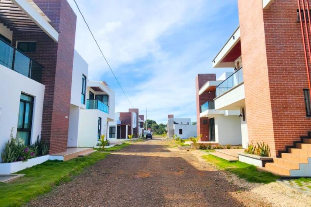 A modern residential area with two-story houses, a gravel driveway, and a clear sky.