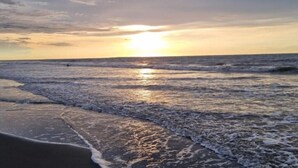 A beach with waves and a sunset.