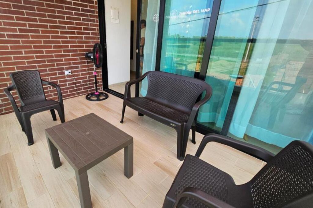 Ein Balkon mit zwei Stühlen, einem kleinen Tisch und einem Ventilator.