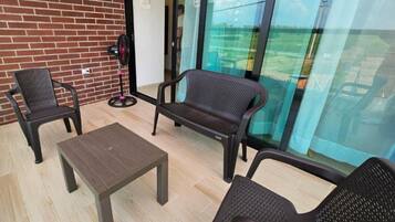 Ein Balkon mit zwei Stühlen, einem kleinen Tisch und einem Ventilator.