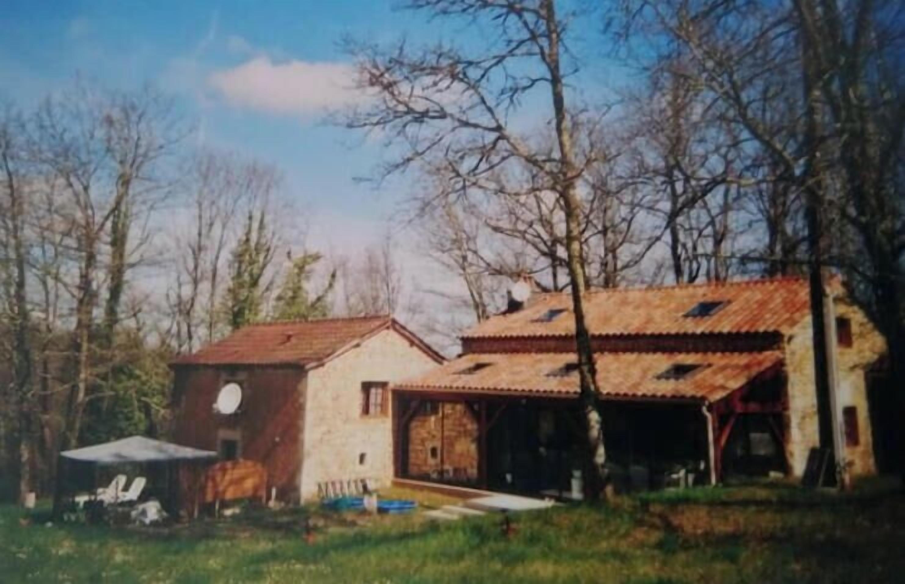 Una casa rustica con tetto rosso, un garage e un piccolo deposito.