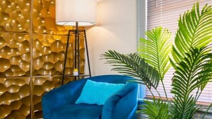 A blue sofa, a floor lamp, a patterned wall, and a potted plant in a room with wooden flooring. - Spacious 4BR Home Near Niagara Falls State Park | Sleeps 10 | Pet-Friendly (Niagara Falls)