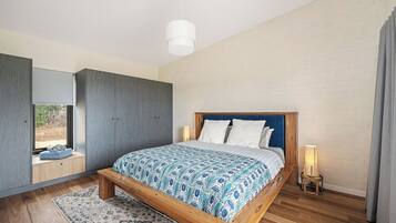 A modern bedroom with a wooden bed, a large window, and a built-in wardrobe.