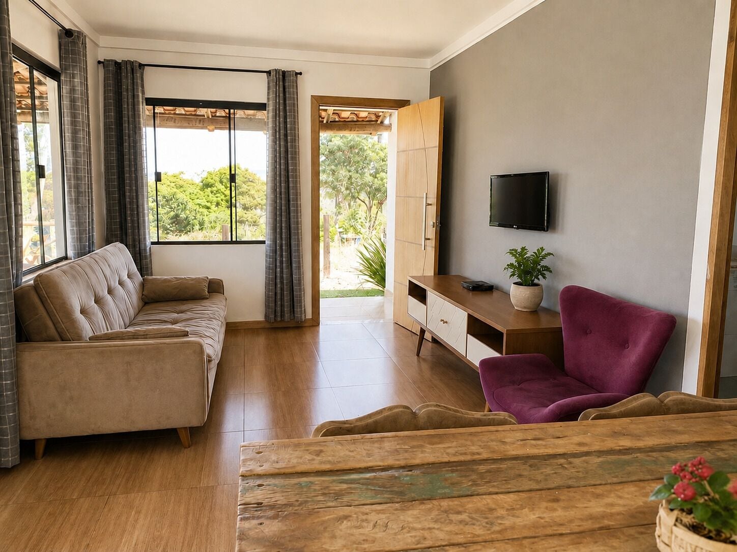 A living room with a sofa, a wooden coffee table, a TV, and a desk with a plant.