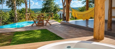 A pool area with a hot tub, wooden deck, and a hammock.