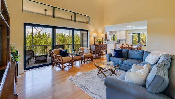 A spacious living room with a large sofa, a dining area, and a kitchen visible through an open door. - Charming pool home in Sea Oats, Sanibel Island (Sanibel)
