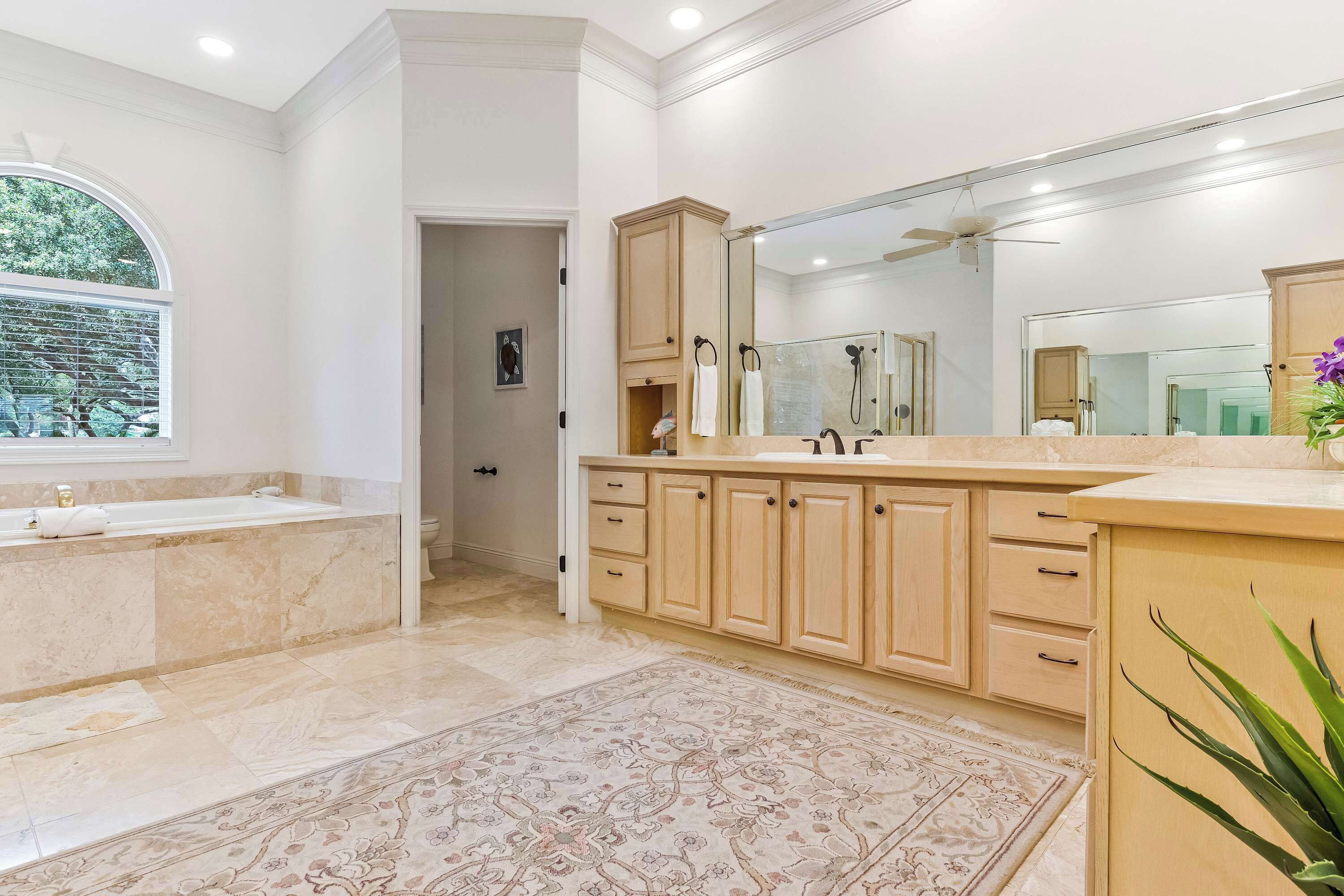 Une salle de bain avec une baignoire, un grand miroir et un meuble-lavabo avec des tiroirs.