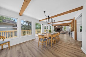 Un amplio comedor con mesa y sillas de madera, ventanas grandes y vistas al exterior.
