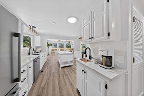 Una cucina moderna con mobili bianchi, una macchina da caffè e vista all'esterno.