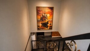 A staircase with a railing and a painting of a ship on the wall.