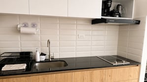 Una cuina moderna amb taulell negre, un rentaplat amb acabat d'acer inoxidable, armaris de fusta i una cafetera a una estant.