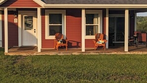 A red building with a white door, two wooden chairs, and a sign reading 'The Gables.'
