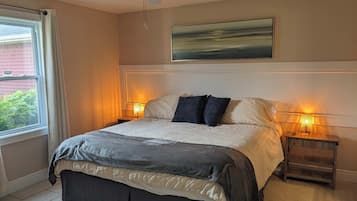 Une chambre à coucher avec un lit, un ventilateur de plafond, deux lampes de chevet, une fenêtre avec des rideaux et un tableau au mur.