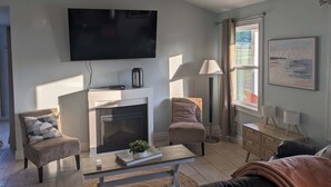 A living room with a fireplace, a television, a sofa, a coffee table, and a lamp.