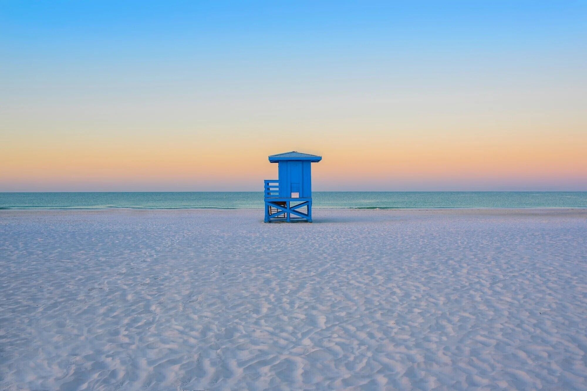 Ein Rettungsturm an einem Strand bei blauem Himmel.