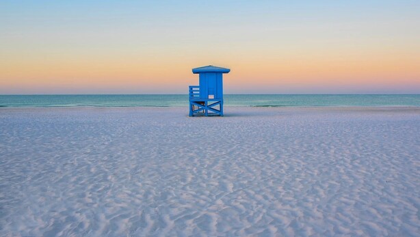 Una torre de salvavidas en una playa con cielo despejado.