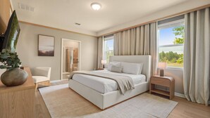 Ein Schlafzimmer mit Bett, Nachttisch und einem großen Fenster mit Vorhängen.
