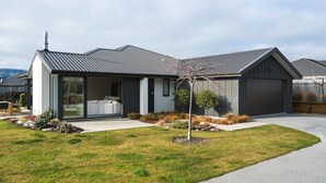 Une maison moderne à deux étages, dotée d’un garage, de grandes fenêtres et d’une pelouse bien entretenue.