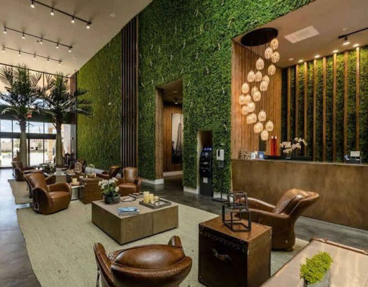 A lobby with a green wall, leather chairs, a reception desk, and a hanging light fixture.