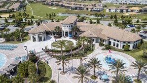 Luchtbeeld van een resort met een centrale binnenplaats, meerdere zwembaden en een golfbaan op de achtergrond.