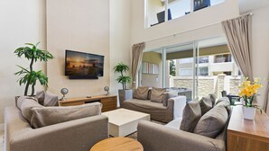 Ein modernes Wohnzimmer mit einer Sofagarnitur, einem Couchtisch und zwei Blumentöpfen.