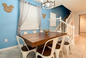 A dining area with a wooden table, white chairs, a chandelier, and a staircase. - Last Minute Disney! Private Pool, Game Room & Themed Bedrooms. Book Now! #170359 (Orlando)