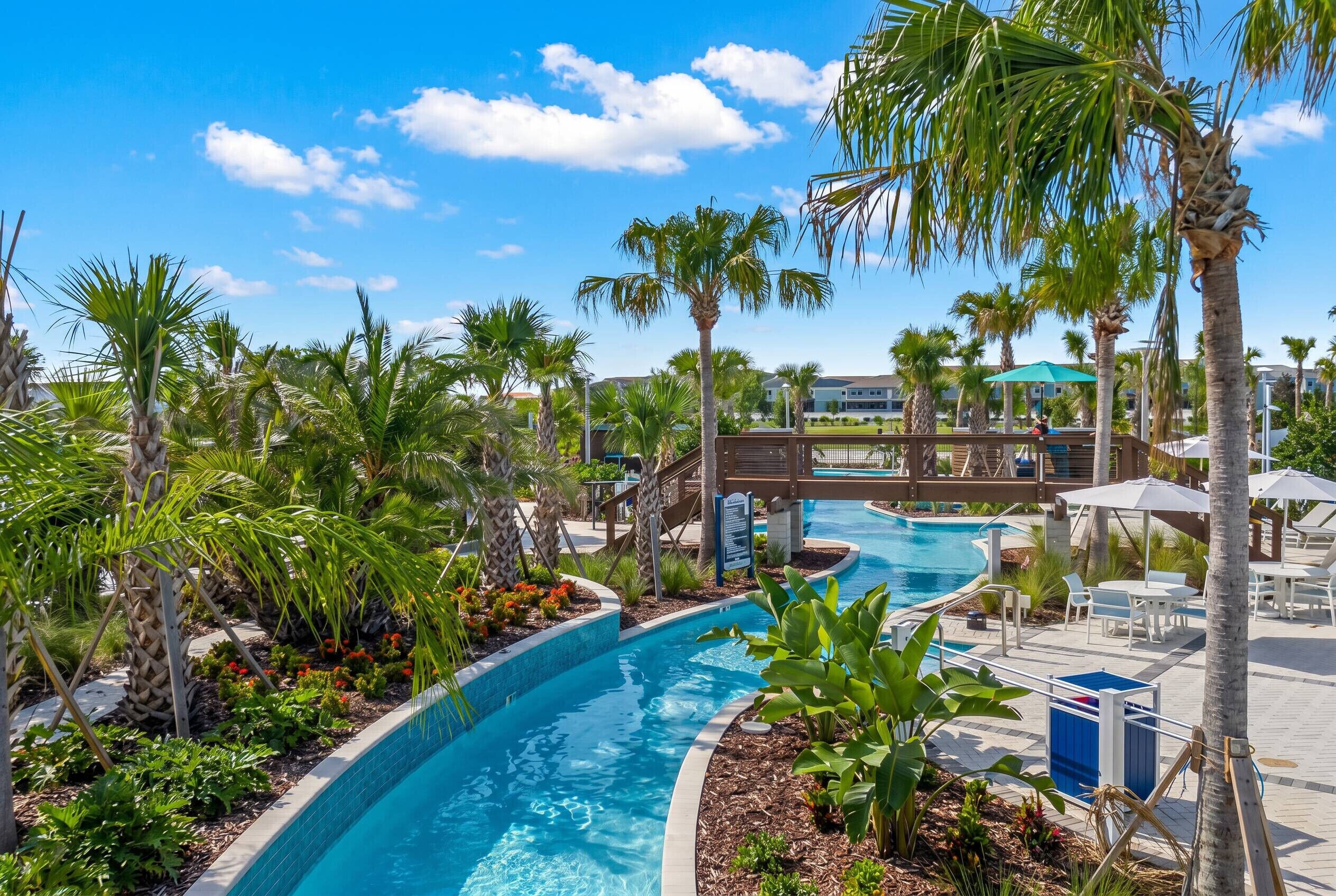 A pool area with palm trees, a wooden bridge, and lounge chairs.