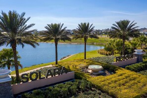 Ein Resort namens Solara mit Blick auf einen See, Palmen und einer gepflegten Rasenfläche.