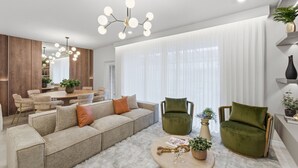 Ein modernes Wohnzimmer mit einer Eckcouch, zwei Sesseln, einem Couchtisch und einem Essbereich mit Tisch und Stühlen.