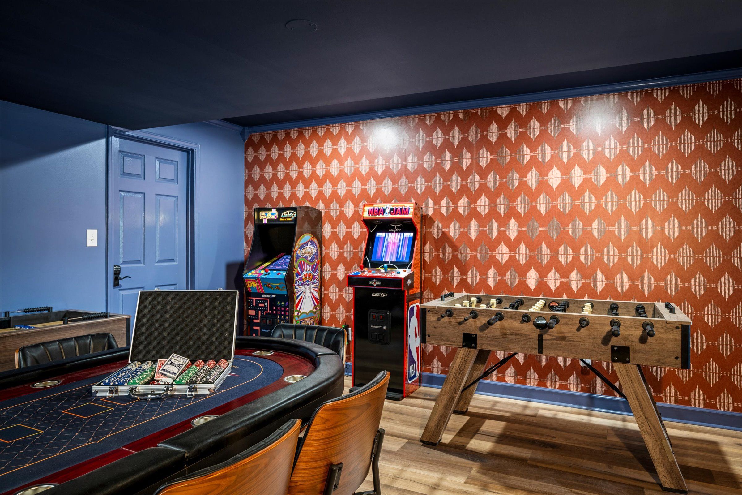 A room with a pool table, foosball table, and two arcade games.