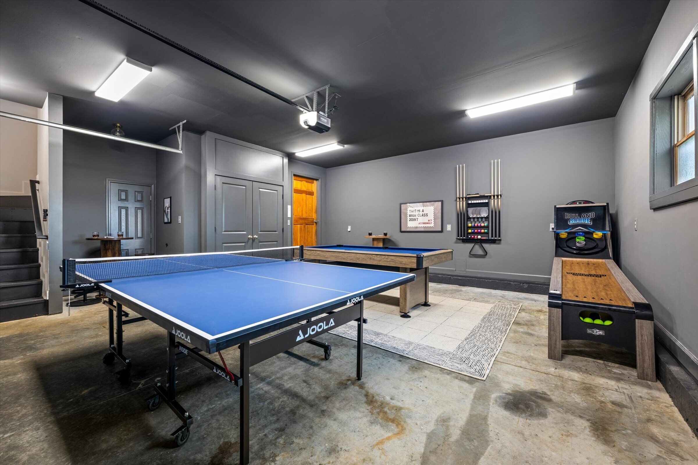 A room with two ping pong tables, a foosball table, and a billiards table.