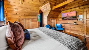 A cozy wooden cabin room with a bed, a desk, and a chair.