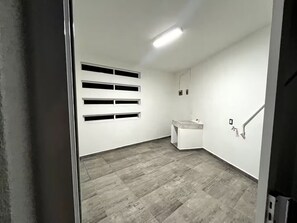 A room with a grey tiled floor, a white wall with a built-in sink, and a ceiling light.