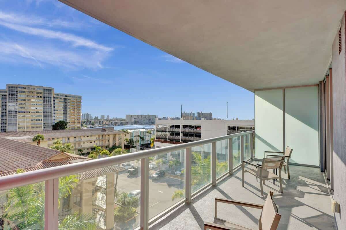 A balcony with a view of a cityscape, including high-rise buildings and a parking lot.