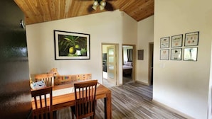 A dining area with a wooden table and chairs, a ceiling fan, and framed certificates on the wall. - Hawaii's Trivia Hale an Off the Beaten Path Oasis | AC | Family Friendly (Mountain View)