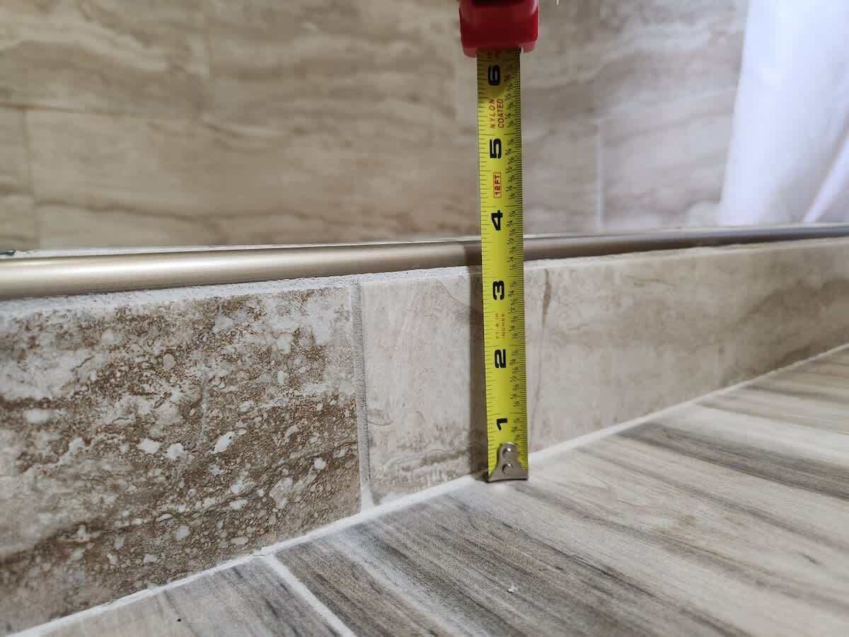 A measuring tape against a tiled wall.