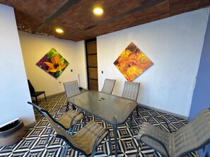 Ein Konferenzraum mit Glastisch, Metallstühlen, einem gemusterten Boden und zwei floralen Bildern an den Wänden.