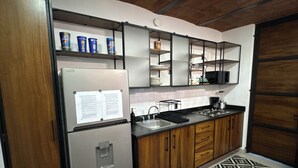 Une cuisine équipée d’un réfrigérateur, d’un four à micro-ondes, d’un évier et de meubles de rangement en bois.