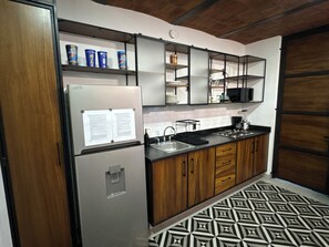Eine Küche mit Kühlschrank, Mikrowelle, Spüle und Holzschränken.
