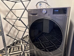 A front-loading washing machine with a digital display, a metal drying rack, and a patterned floor. - Apt in Guadalajara Americana / Downtown • SuperFast Wifi • Walking rate 100% (Guadalajara)