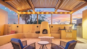 Eine Terrasse im Freien mit einer Pergola, Lichterketten, einem Grill und Sitzgelegenheiten.