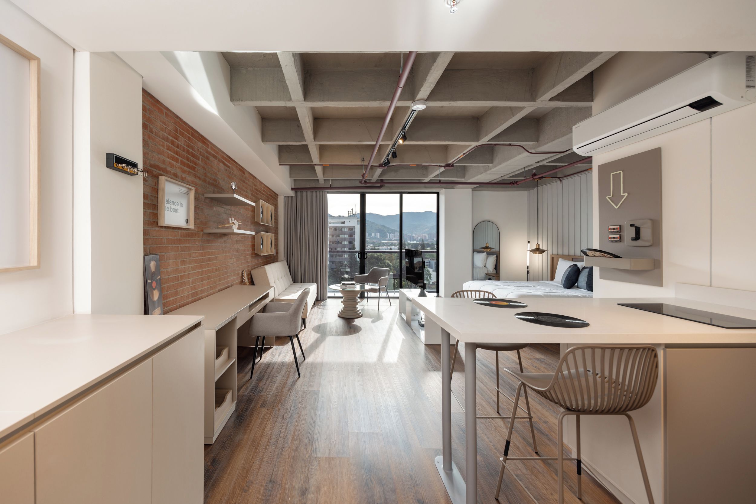 A modern interior with a kitchen, dining area, and a large window offering a city view.