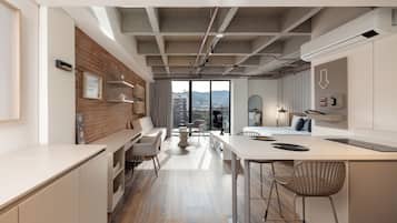 A modern interior with a kitchen, dining area, and a large window offering a city view.