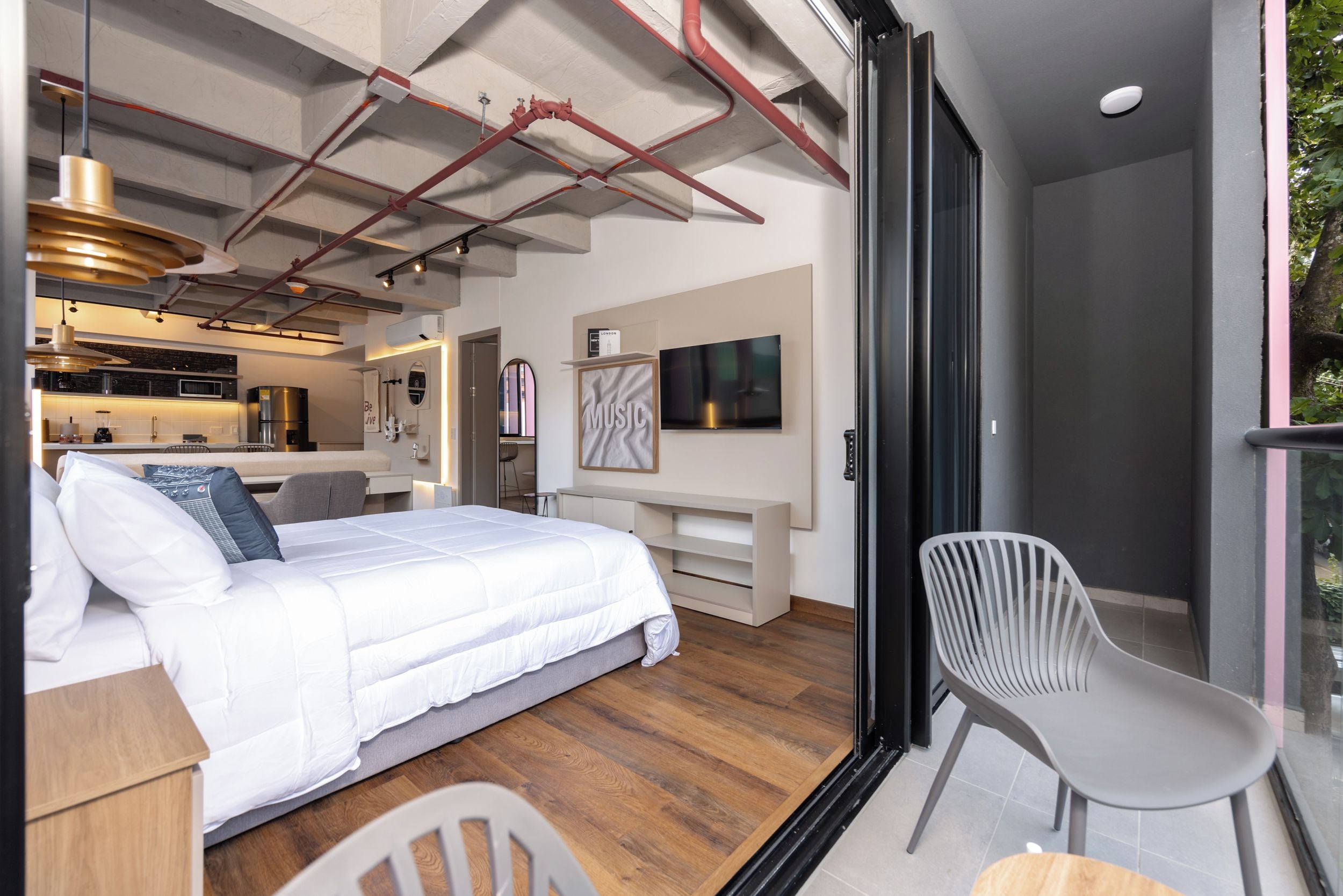 Un dormitorio moderno con cama, escritorio, silla y televisor.