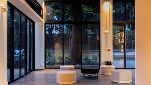 Un vestíbulo moderno con amplias ventanas, un árbol y tres zonas de estar circulares.